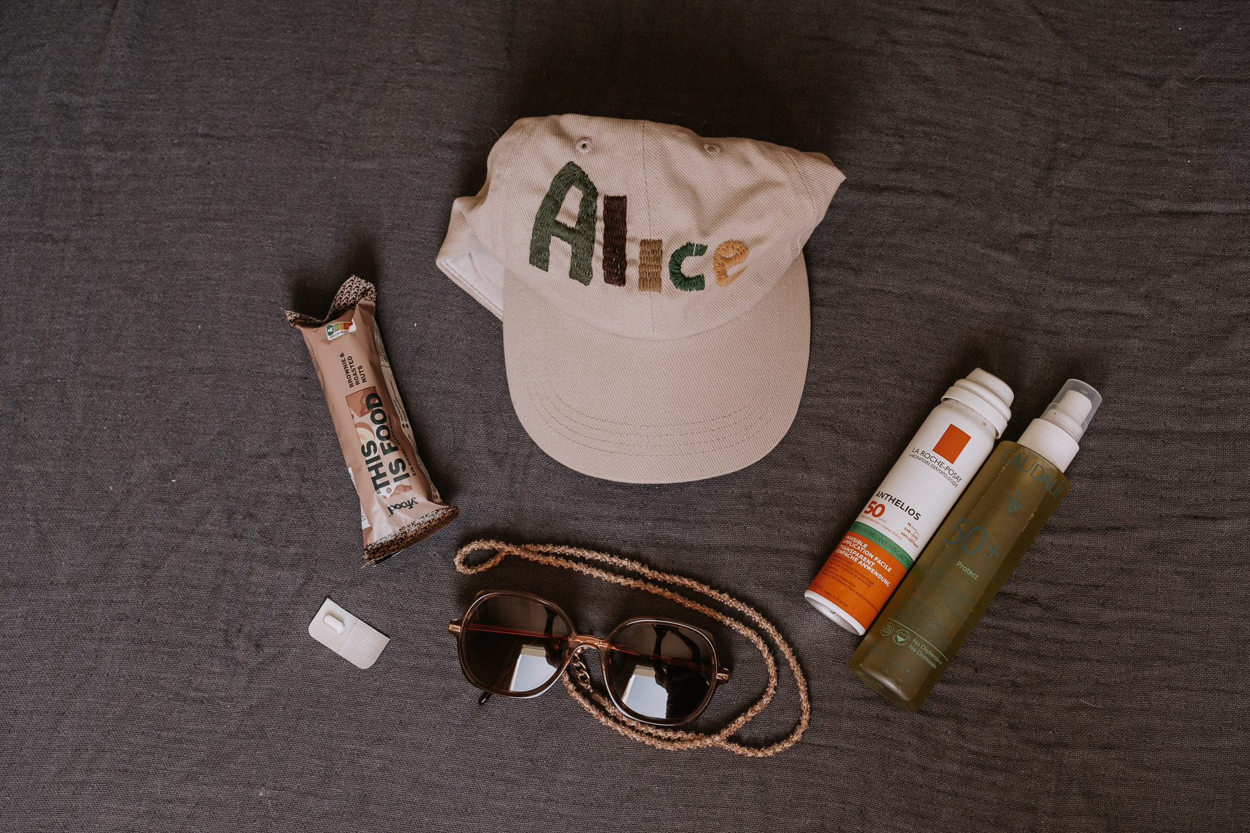 a hat and sunglasses and other items on a bed