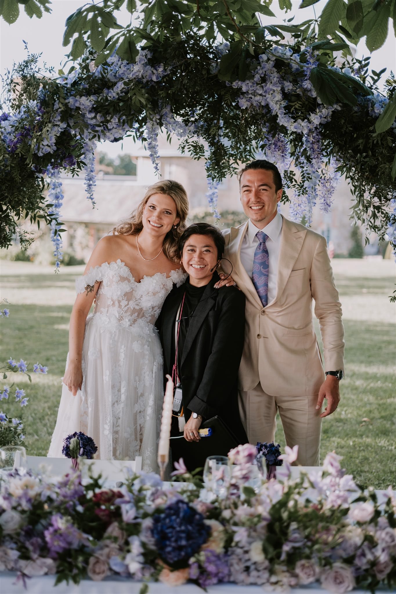 a group of people posing for a picture under a floral arch